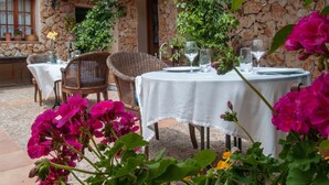 An outdoor patio with stone walls, wicker furniture, and tables set for dining. - Agroturismo Son Ginebró (Inca)