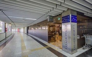 Un interior de hotel moderno con una zona de recepción, un letrero de salida visible y un camino despejado.