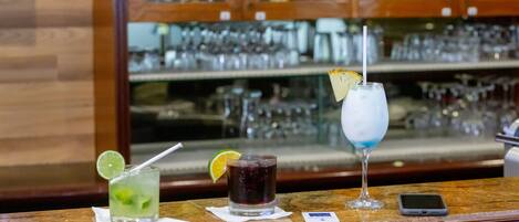 A bar counter with three drinks and a smartphone.