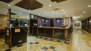 A hotel reception area with a check-in counter, a seating area, and a view of the lobby. - Rio Aeroporto Hotel Galeão (Rio de Janeiro)