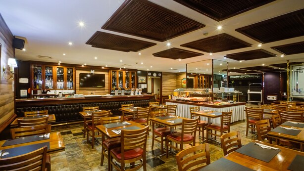 A restaurant with wooden tables and chairs, a bar area, and a buffet. - Rio Aeroporto Hotel Galeão (Rio de Janeiro)