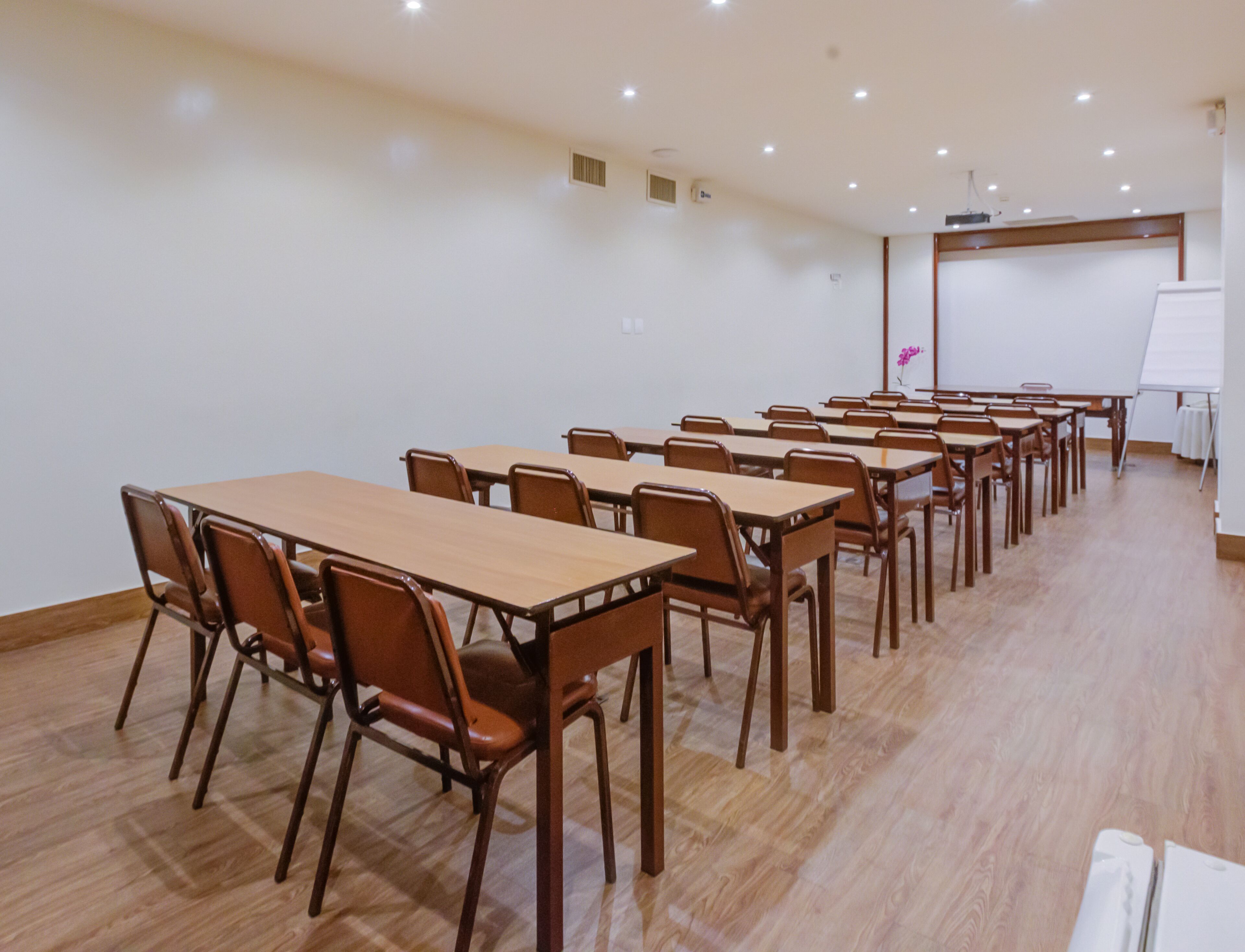 A conference room with multiple tables and chairs, a whiteboard, and a projector screen.