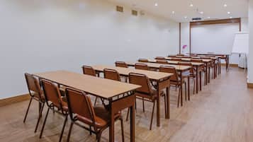 A conference room with multiple tables and chairs, a whiteboard, and a projector screen.