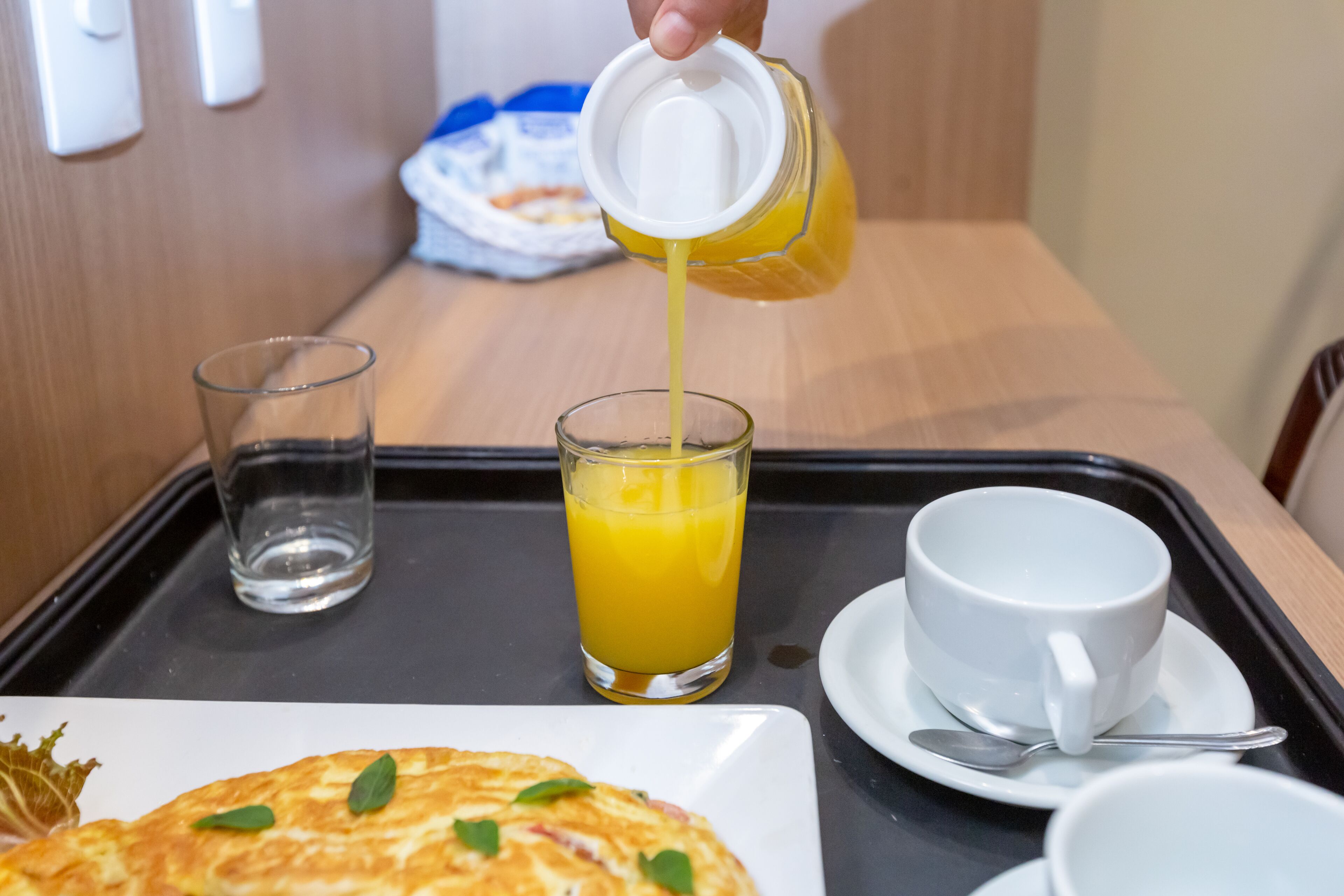 Una bandeja de desayuno con un vaso de jugo de naranja, una taza de café y un plato de comida.