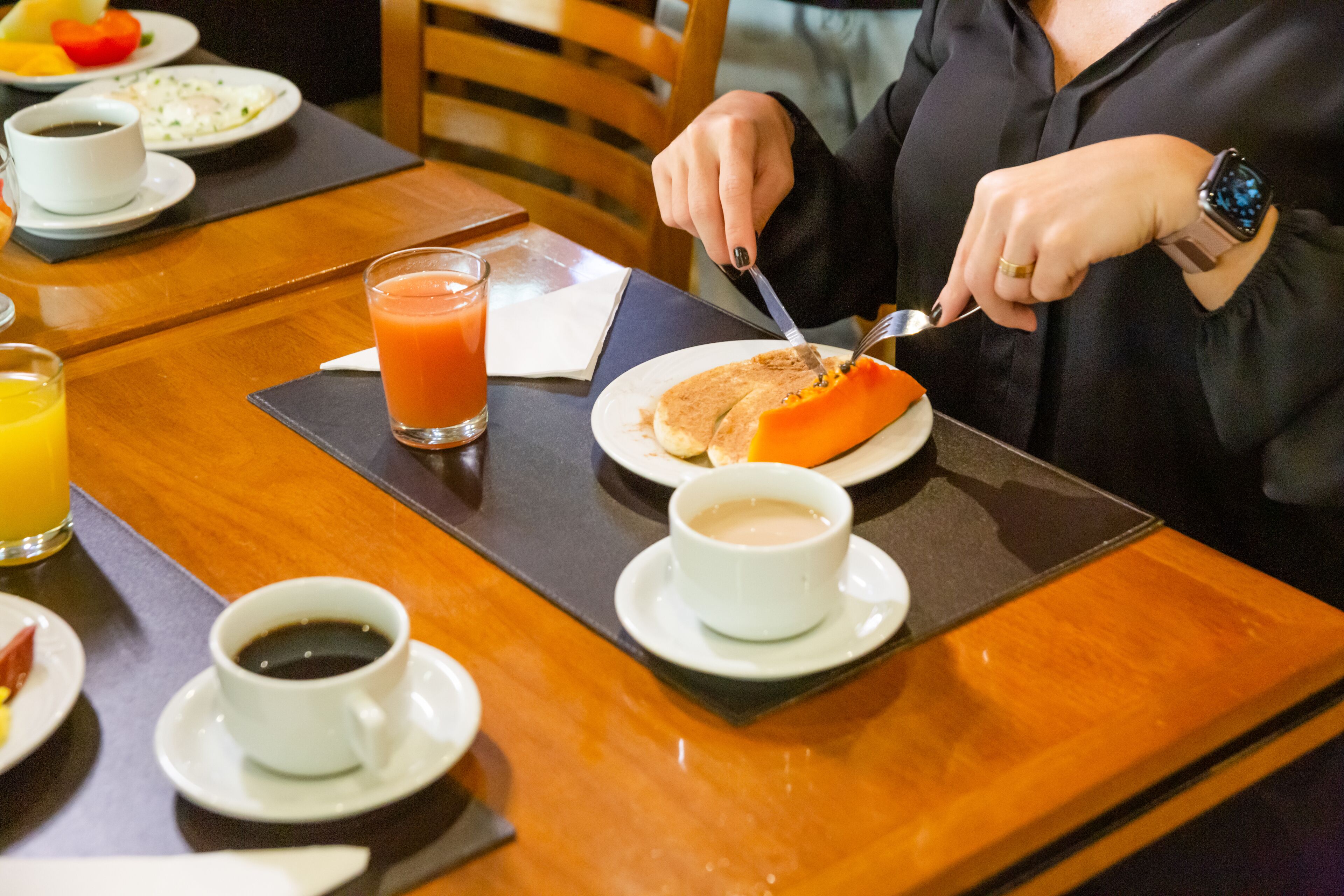 A breakfast setting with a plate of food, a glass of orange juice, and a cup of coffee on a wooden table.
