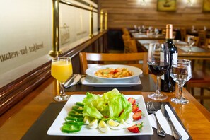 Una mesa de comedor con un plato de comida, una botella de vino y una copa de vino tinto.