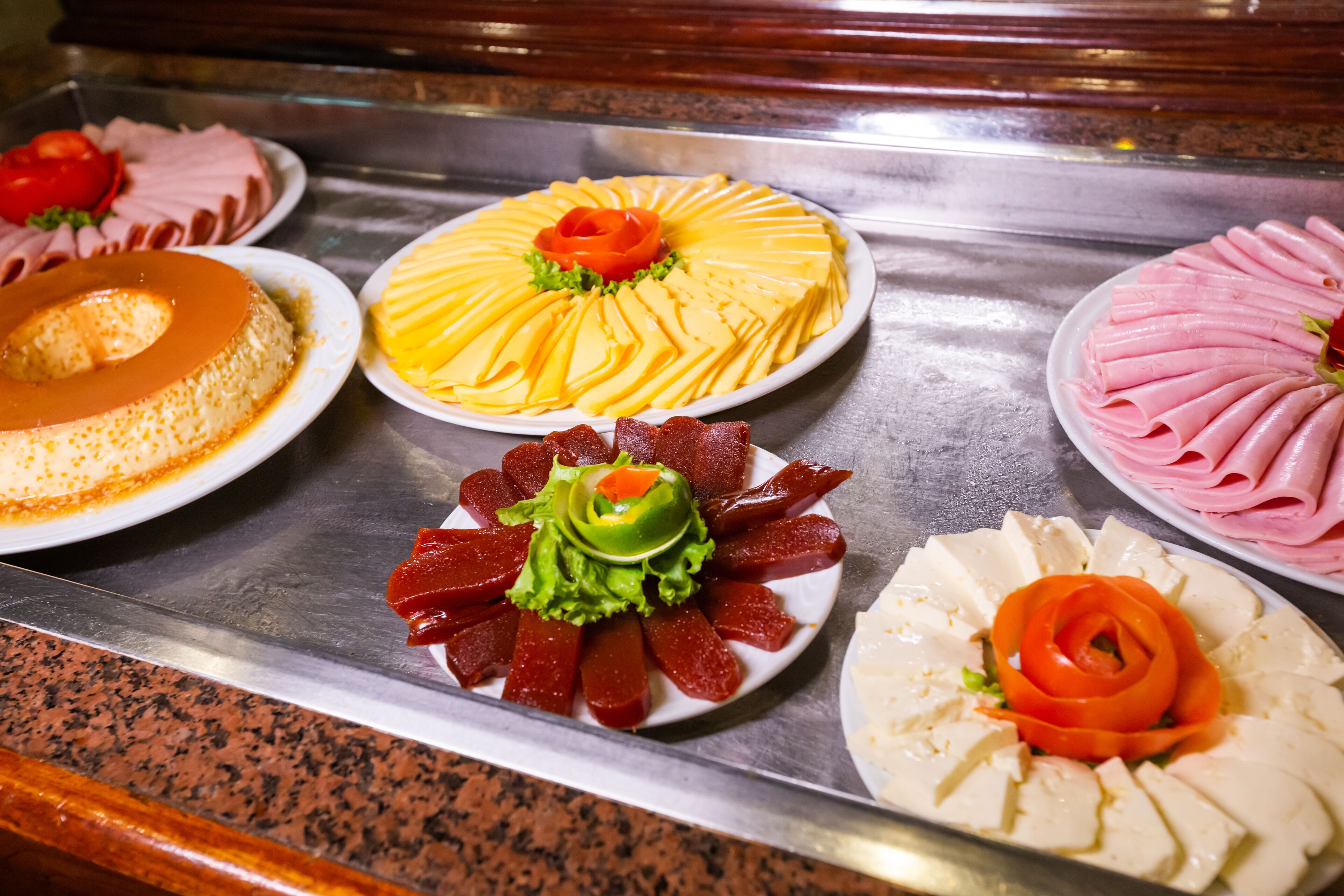 A buffet with various dishes including a round cake, a yellow layered dish, and several meat platters.