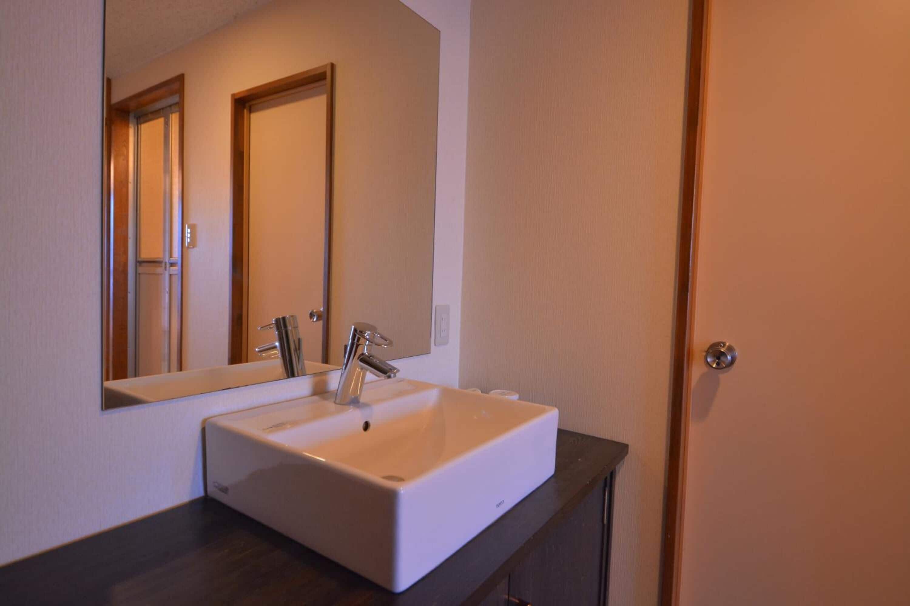 A bathroom with a white sink, a mirror, and a door.