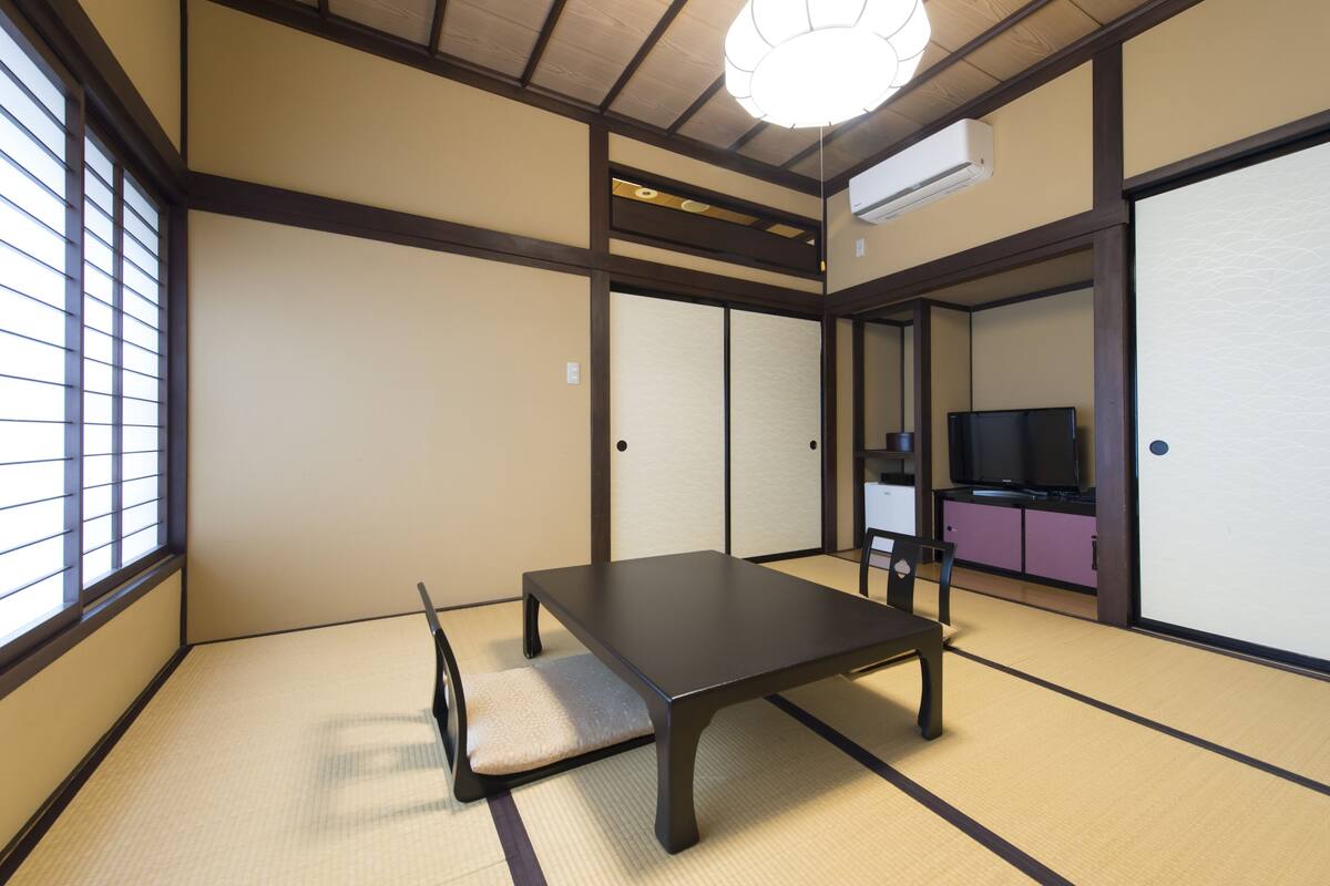 A traditional Japanese room with tatami flooring, a low table, and sliding doors.