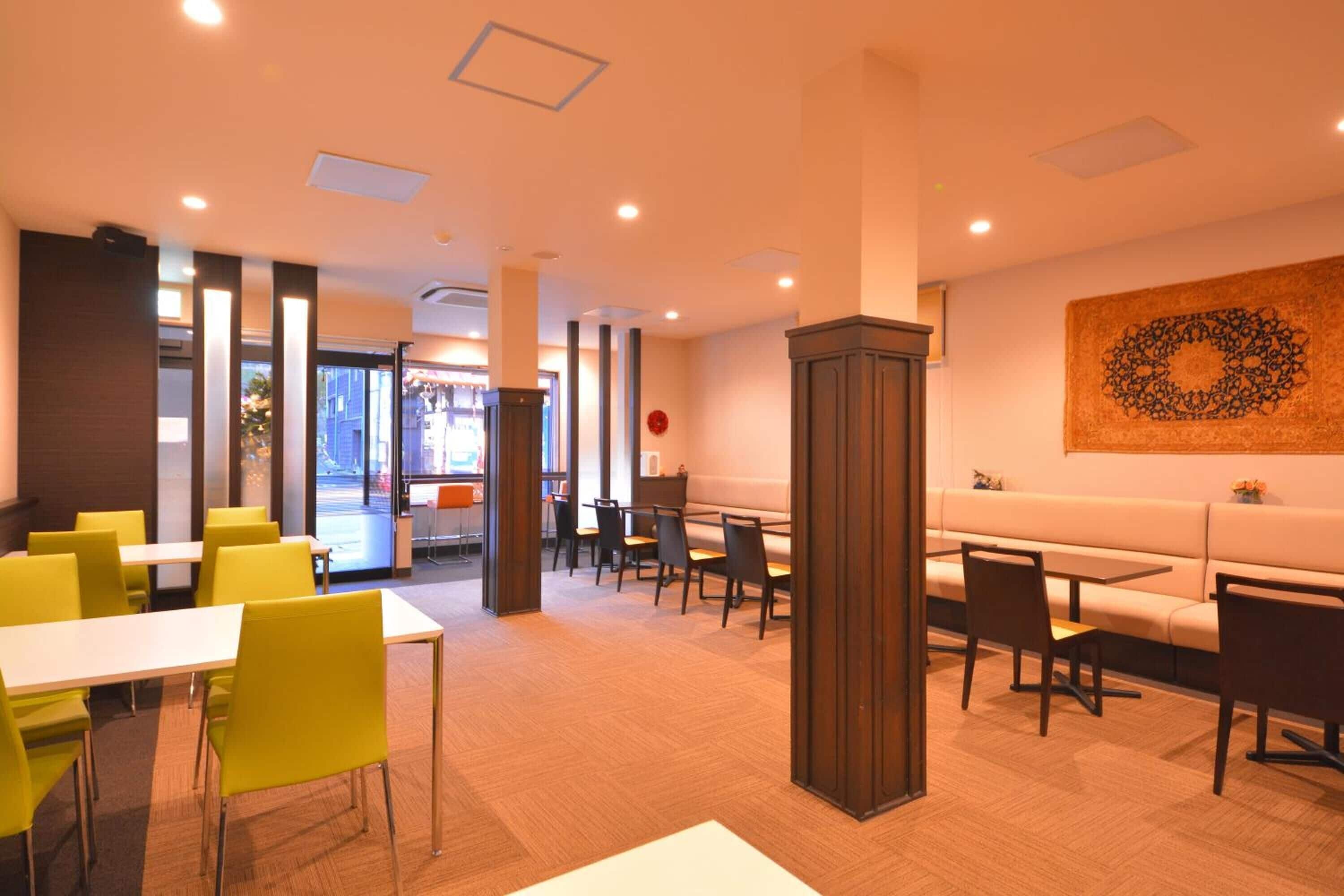 A modern restaurant with yellow chairs, white tables, and a large decorative wall piece.