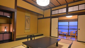 A traditional Japanese room with tatami flooring, a low table, and sliding doors leading to a balcony with a view. - Nikko Tokino Yuu (Nikko)