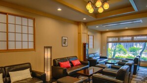 A hotel lobby with leather sofas, a coffee table, and a traditional Japanese screen. - Nikko Tokino Yuu (Nikko)