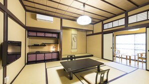 A tatami room with a tatami mat floor, a low table, and a TV on the wall. - Nikko Tokino Yuu (Nikko)