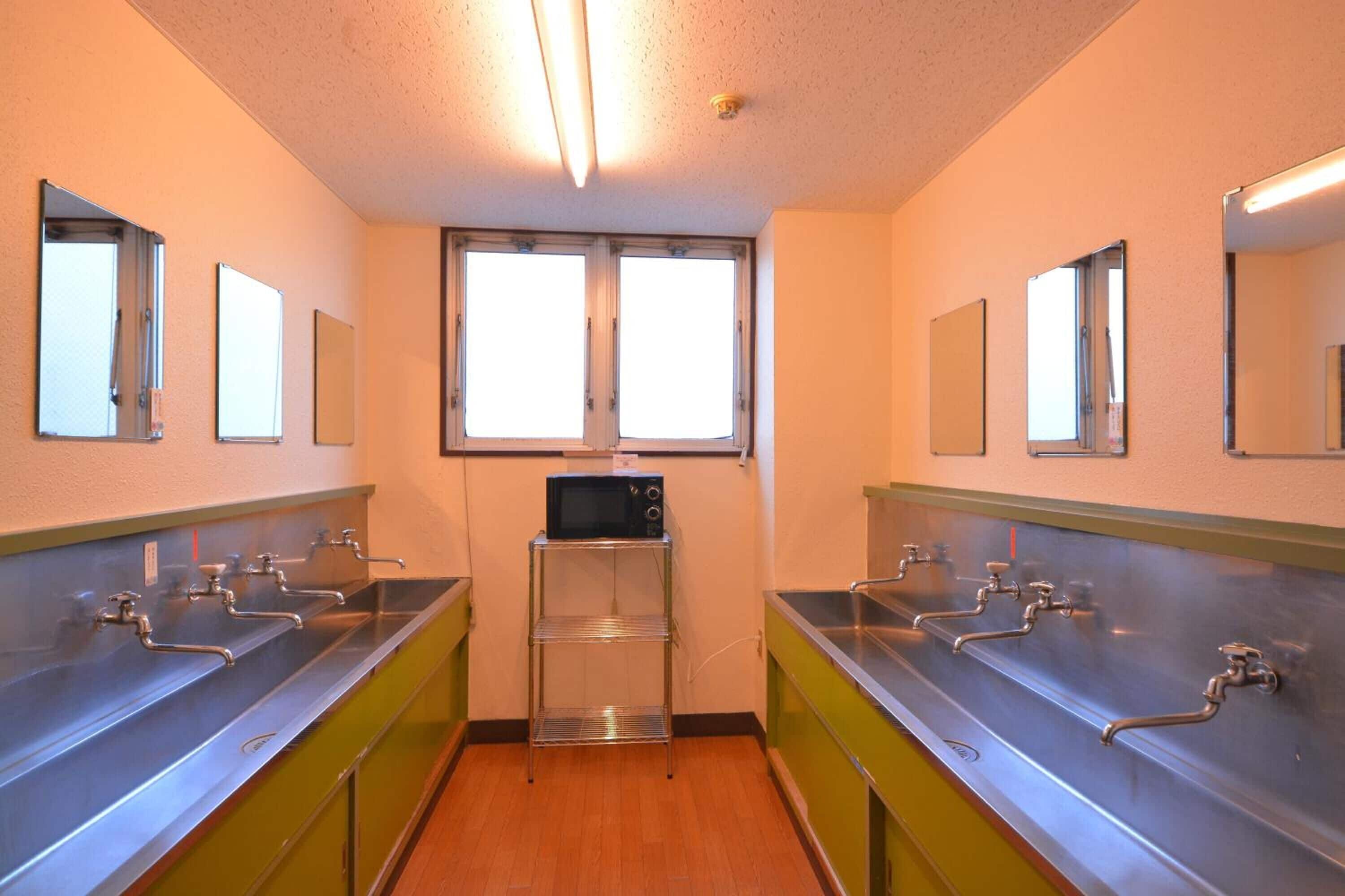 A restroom with multiple sinks, a microwave, and mirrors on the walls.