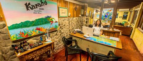 A reception desk with a map, a computer, and a woman standing behind it.