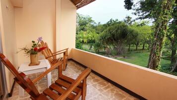 Een balkon met houten stoelen en een kleine tafel met een bloevas.