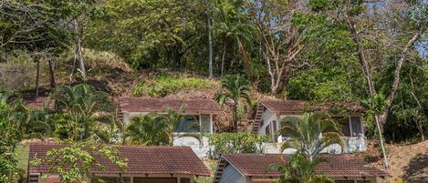 Uma propriedade em encosta com vários edifícios pequenos, cada um com telhado de telhas e paredes de pedra. Há vários espaços de estar ao ar livre com cadeiras.