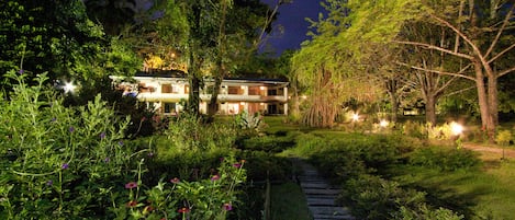 A two-story house with a well-maintained garden and a wooden pathway leading to the entrance.