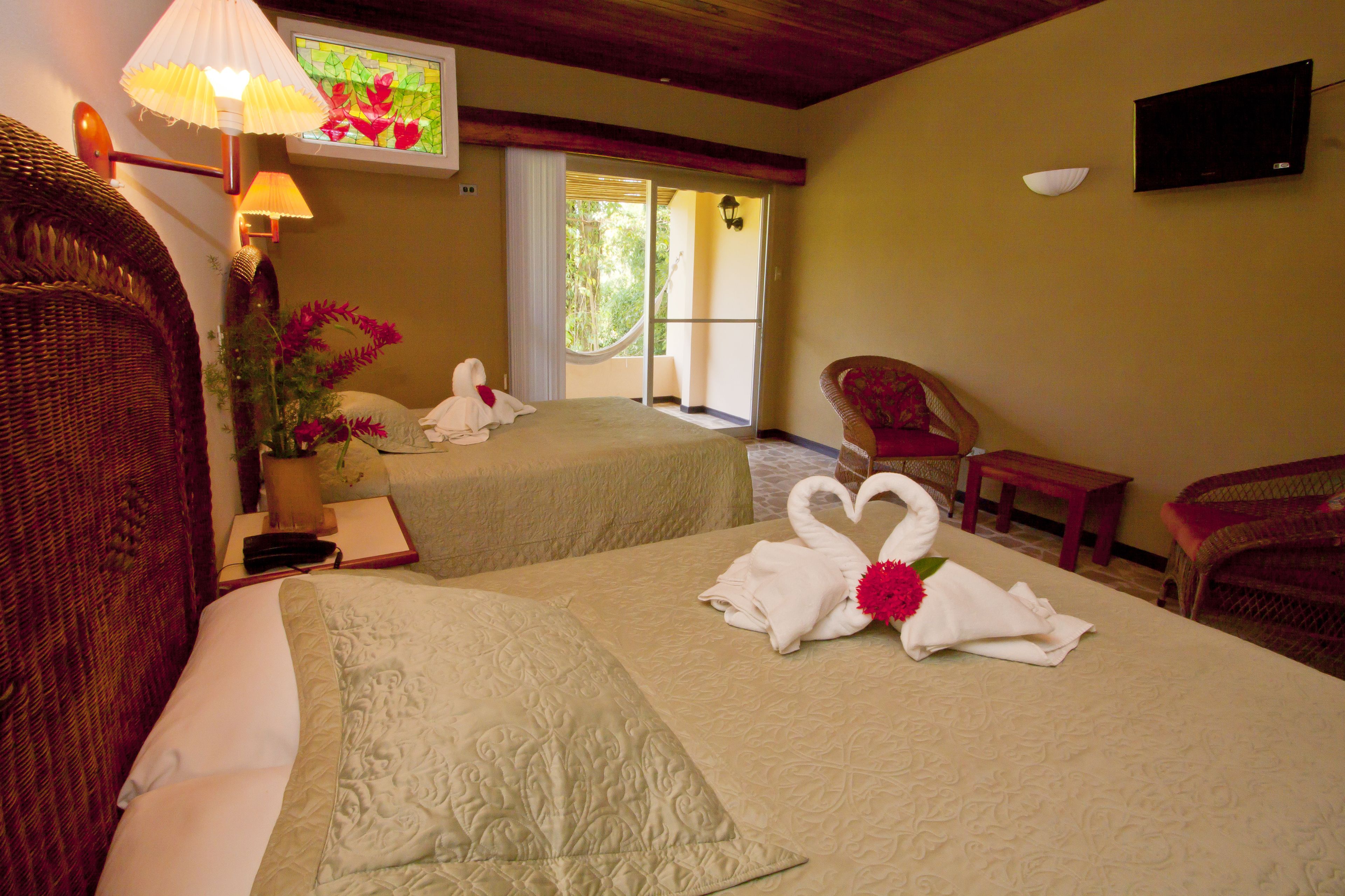 A hotel room with two beds, a TV, a window with a view, and a balcony.