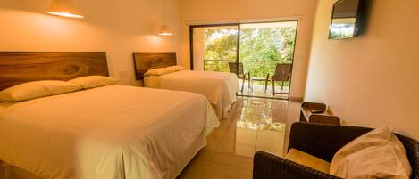 A hotel room with two beds, a balcony with chairs, and a television on the wall.