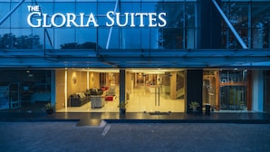 The exterior of The Gloria Suites hotel with a modern design, large glass windows, and a well-lit entrance. - The Gloria Suites Jakarta (Jakarta)