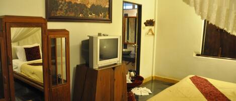 Una habitación de hotel con cama, un armario de madera, un televisor y un cuadro en la pared.