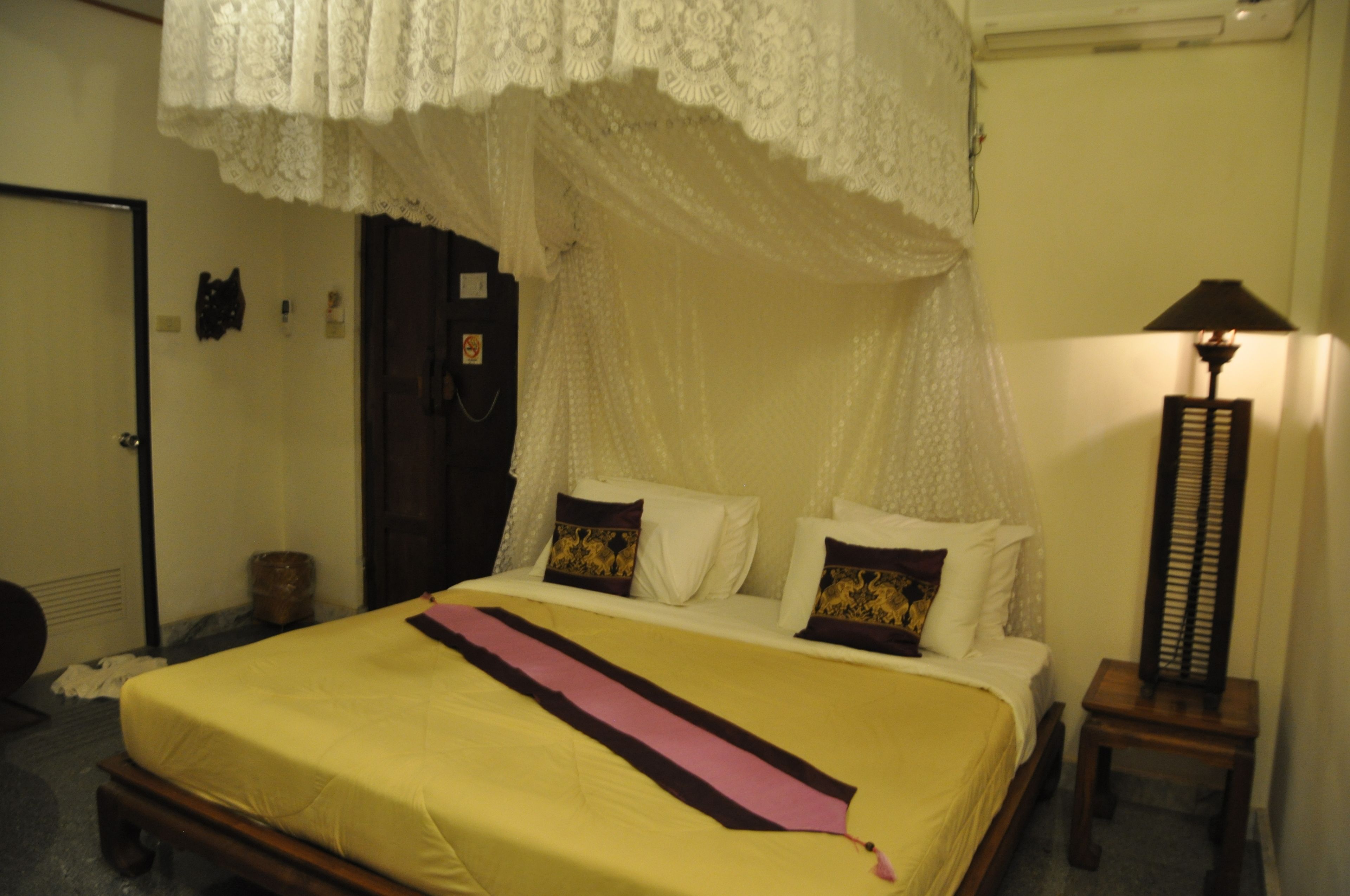A bed with a canopy, a bedside table, and a lamp.