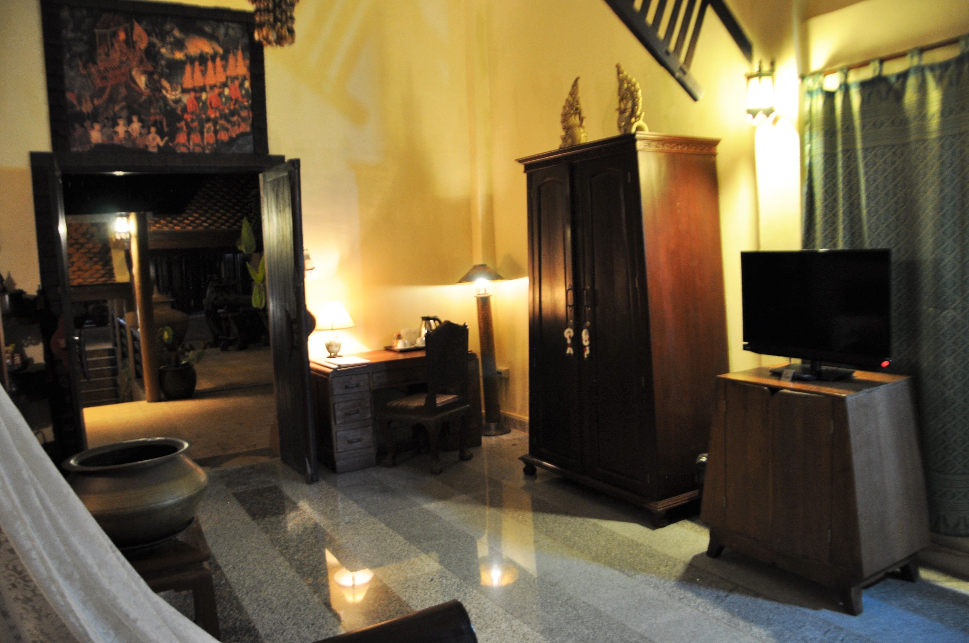 Una habitación con escritorio, silla, televisor y un armario.