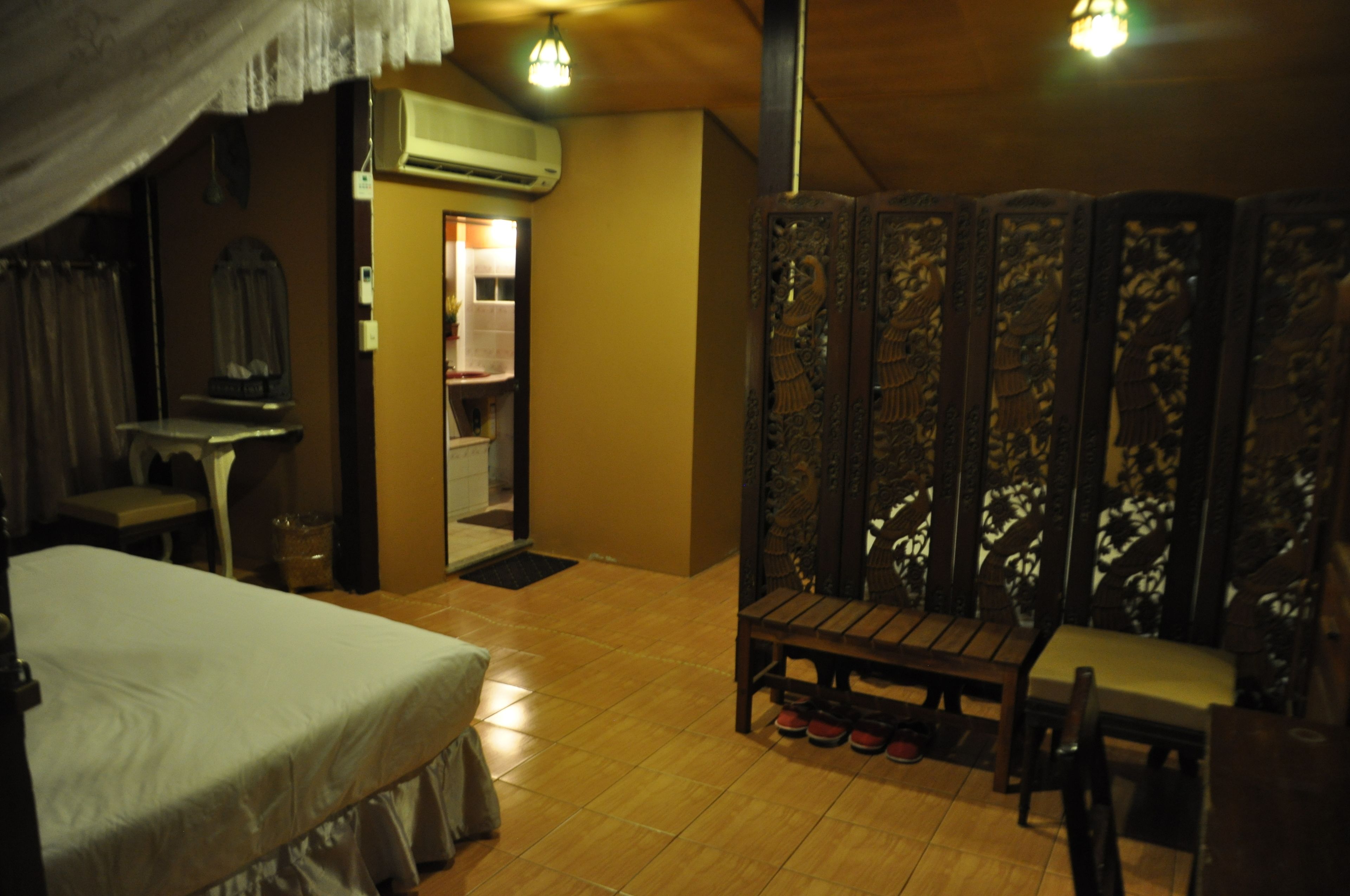 A room with a bed, a wooden bench, a mirror, and a wardrobe with intricate designs.