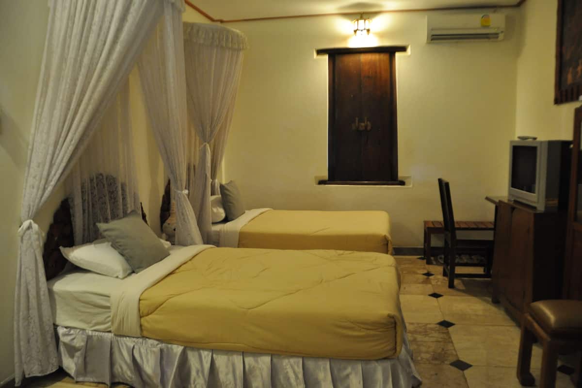 A bedroom with two beds, a TV, and a small table.