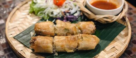 A plate of spring rolls with a side salad and dipping sauce.