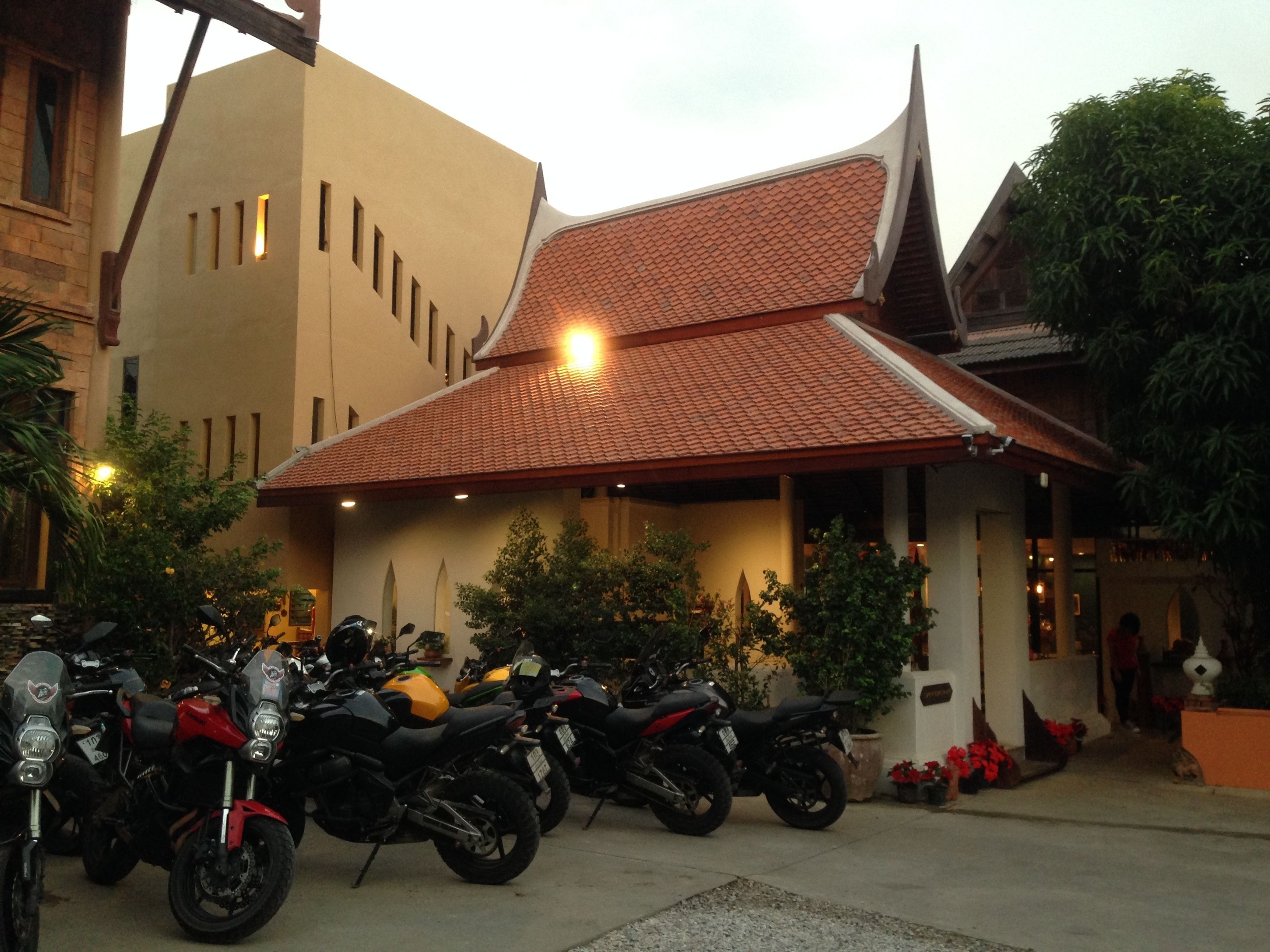 A building with a tiled roof and a parking area with motorcycles.