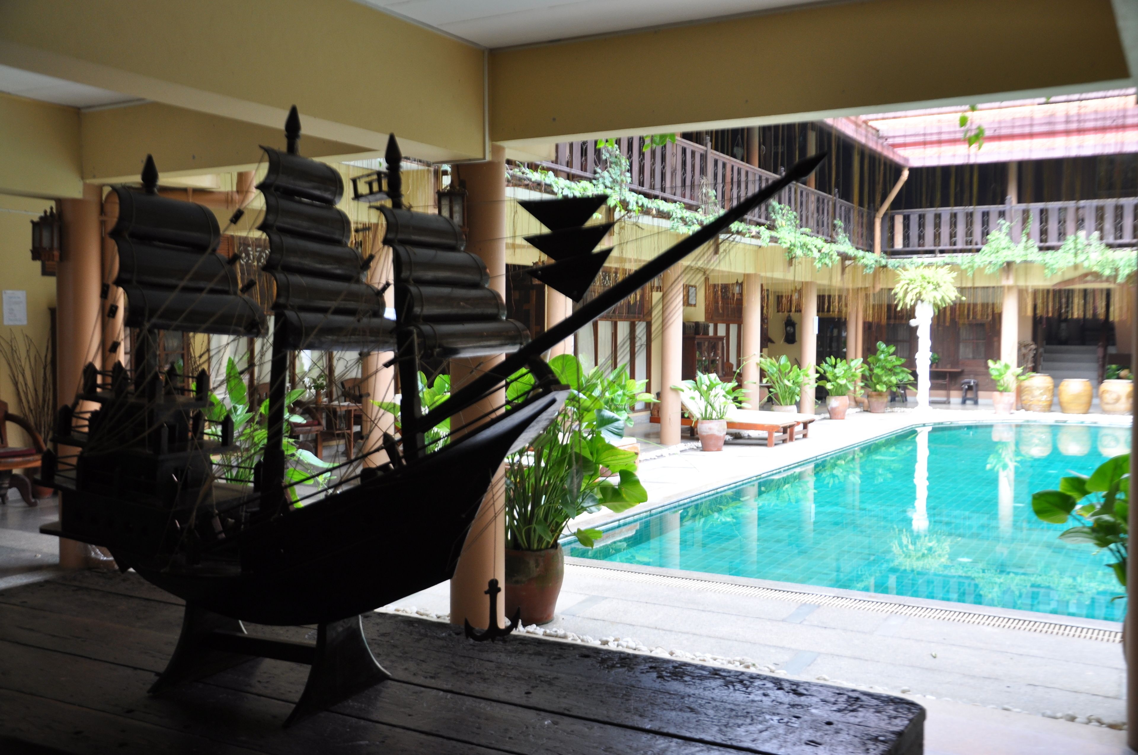 A pool area with a hammock, potted plants, and a staircase leading to an upper level.
