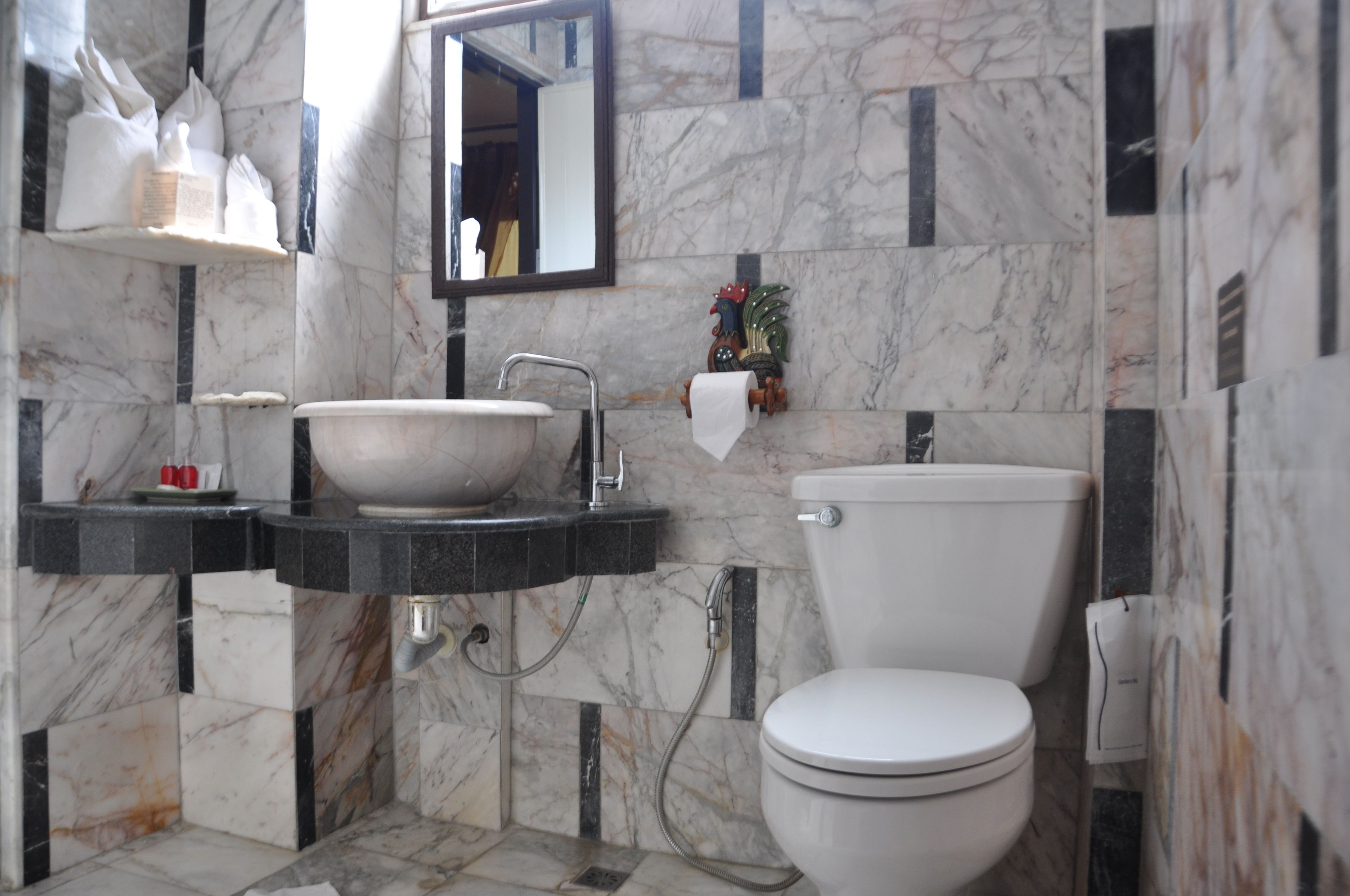 Un baño con lavamanos de mármol, inodoro y espejo.