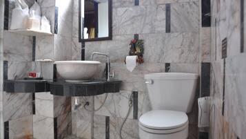Un baño con lavamanos de mármol, inodoro y espejo.