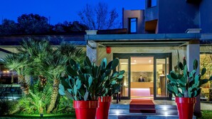 A modern building with a glass entrance, large potted cacti, and a well-lit reception area. - Park Hotel Sabina (Magliano Sabina)