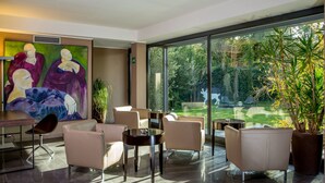 A modern interior with a large window, a painting, and a dining area. - Park Hotel Sabina (Magliano Sabina)
