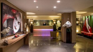 A hotel reception area with a modern design, featuring a reception desk, seating area, and artwork on the walls. - Park Hotel Sabina (Magliano Sabina)