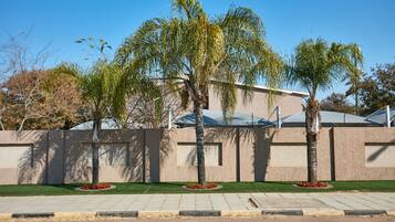 A modern building with a concrete facade, a well-maintained lawn, and several palm trees.