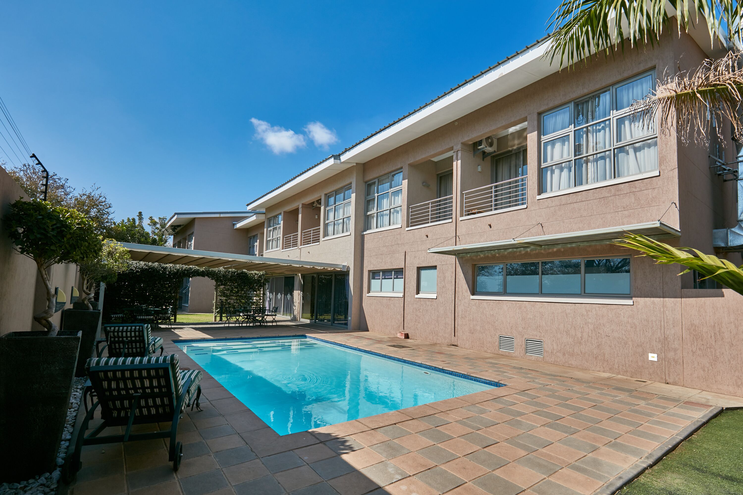 Une maison moderne à deux étages, dotée d’une piscine et d’un espace de détente extérieur.