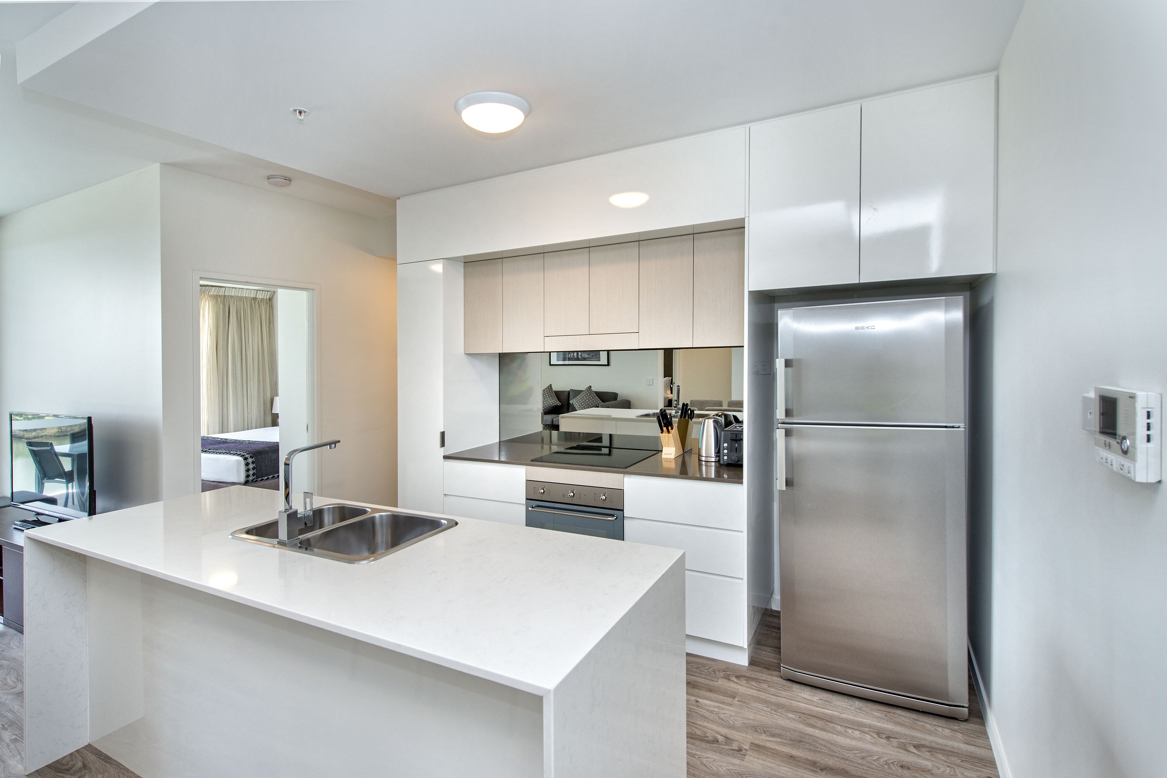 A modern kitchen with white cabinetry, stainless steel appliances, and a central island with a sink.
