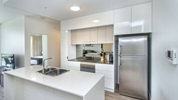 A modern kitchen with white cabinetry, stainless steel appliances, and a central island with a sink.