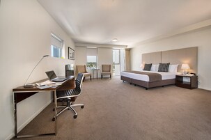 Habitación de hotel con cama, escritorio, silla y vistas al exterior.