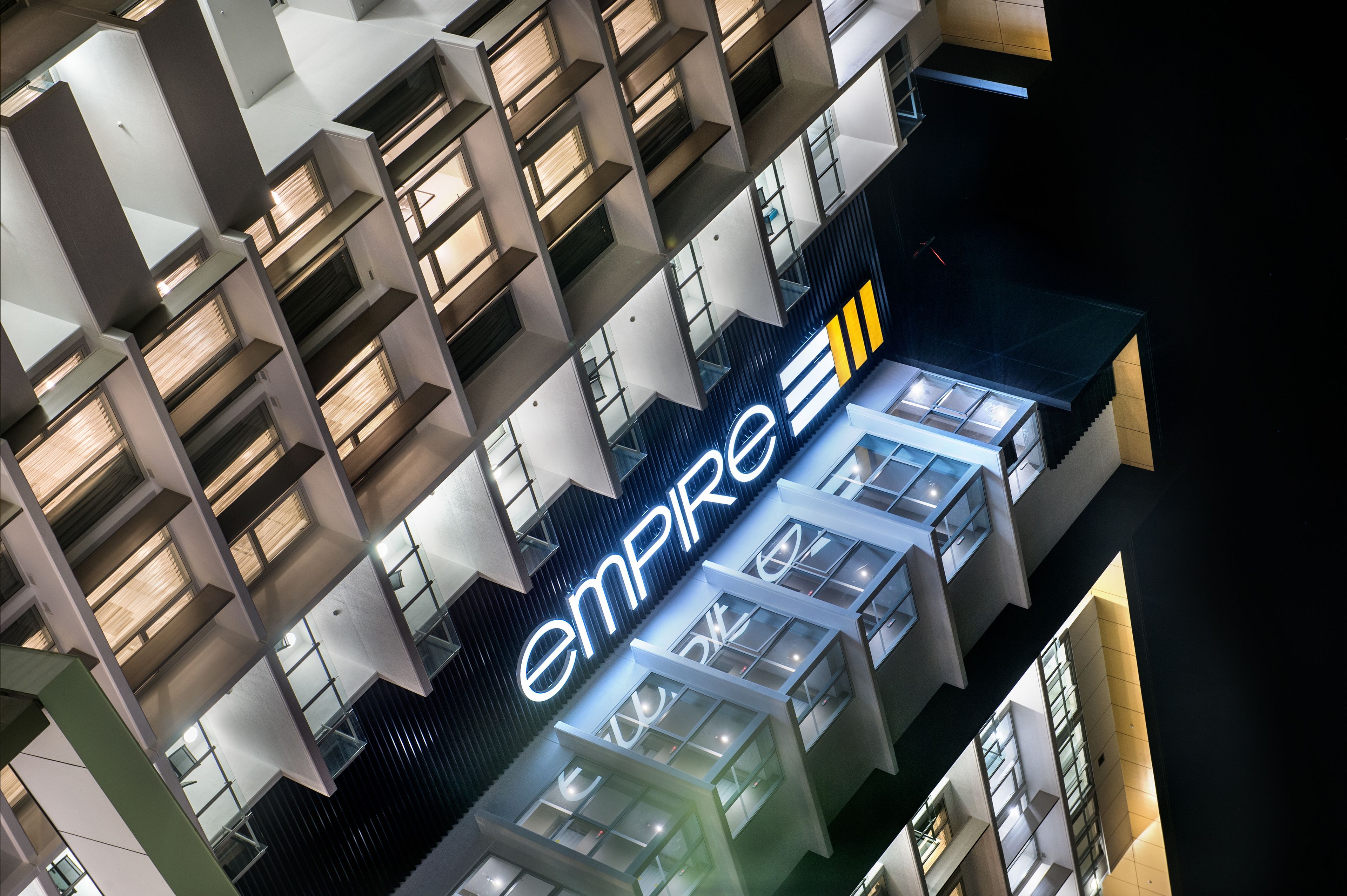 A modern building with a prominent 'Empire' sign, featuring a geometric facade and multiple balconies.