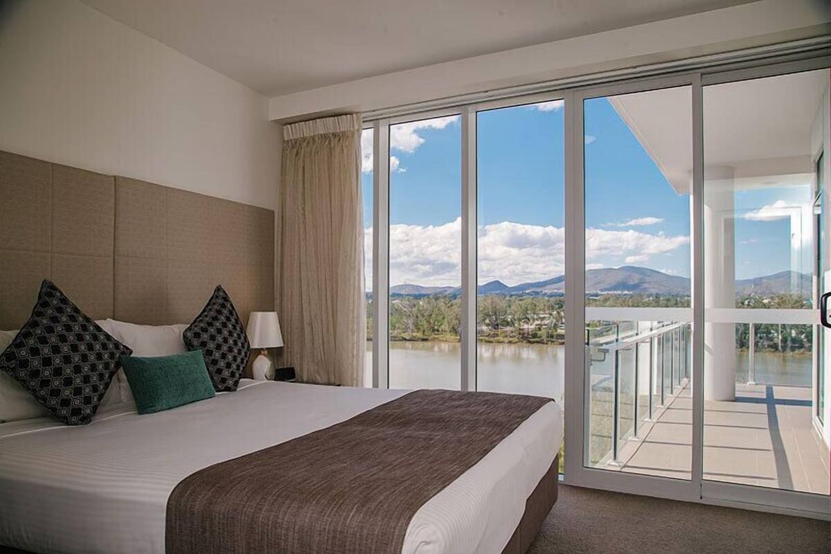Ein Hotelzimmer mit einem großen Bett, Seeblick und einem Balkon.