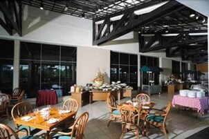 A spacious indoor dining area with high ceilings, large windows, and modern furniture.
