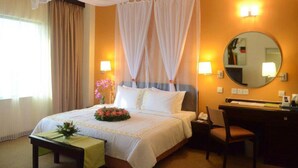A hotel room with a bed, bedside table, chair, desk, and a mirror. - RHR Hotel at Uniten (Kajang)