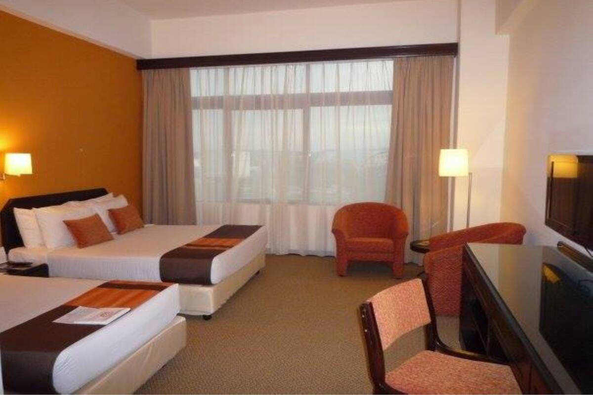 A hotel room with two beds, a TV, a desk, and a chair.