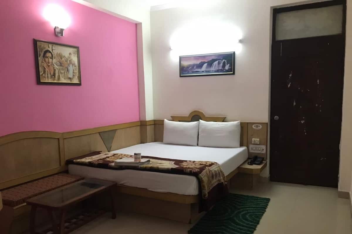 A bedroom with a bed, bedside table, lamp, and a door.