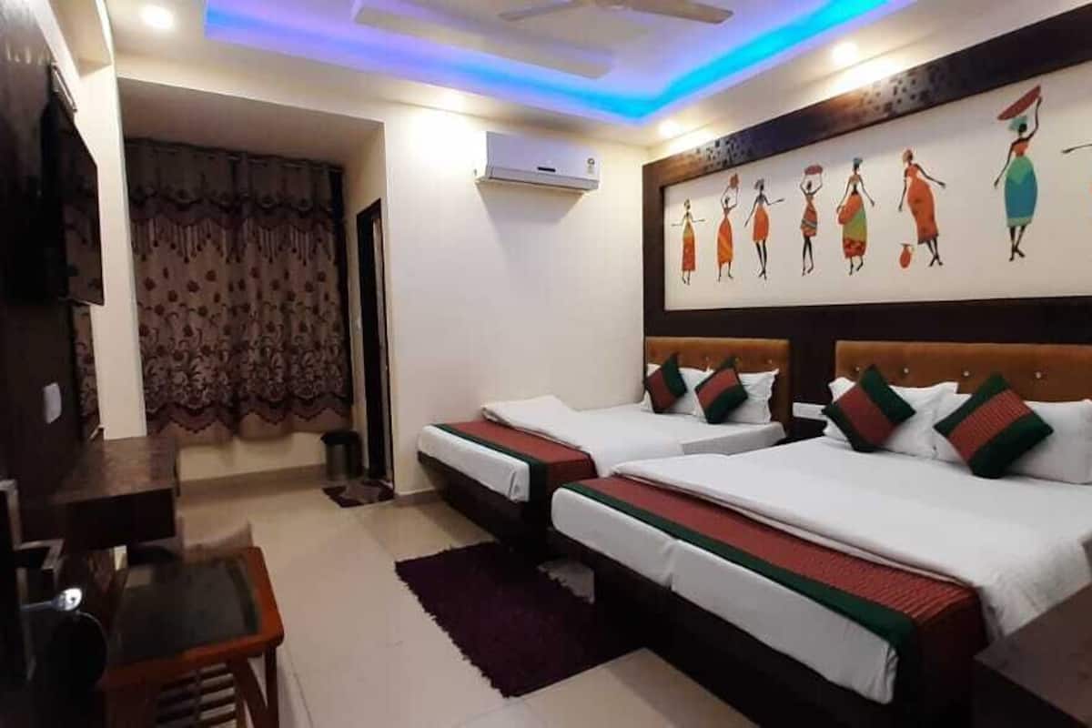 A hotel room with two beds, a desk, a chair, a TV, and a painting on the wall.